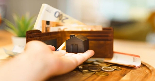 person holding house and coins